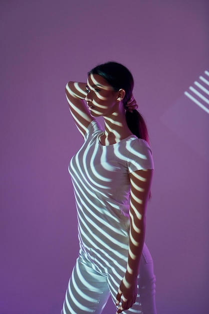 Purple colored background Beautiful young woman is in projector neon lights in the studio