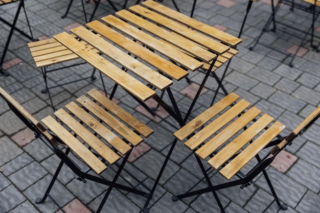 A purple colored metal patio table near a blue wooden horizontal clapboard siding exterior wall There's a white flower pot with pink flowers on the small square table The ground is patio flat rocks