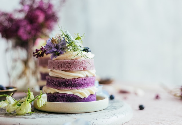 春の花で飾られた紫色のクリームケーキ