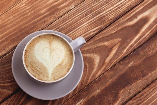 Purple cup of coffee with macaroons on the wooden background