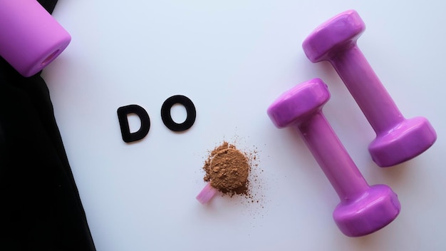 Photo purple dumbbells and protein powder on a black and white background with message to motivate, do it