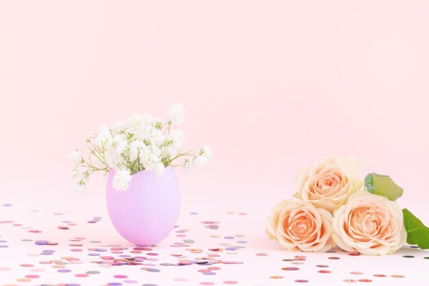 Purple easter eggshell with white gypsophilayelloworange pastel roses pink backgroundmulticolor confetti Egg is symbol of celebration of religious holiday among Catholics ChristiansProtestants