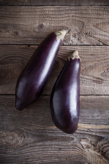 Purple eggplants on wooden background