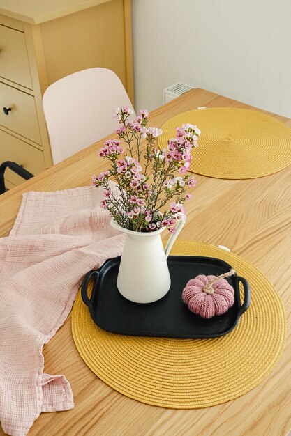 purple flower bouquet in a white jug on the wooden table.