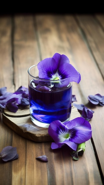 Purple flower in a glass with a purple flower on a wooden board