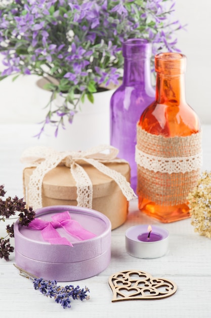 Purple flowers and lit candle on white table