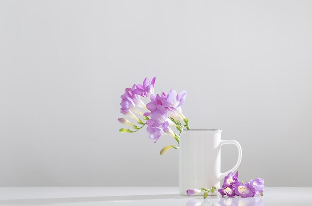 Purple freesia in glass vase on white background