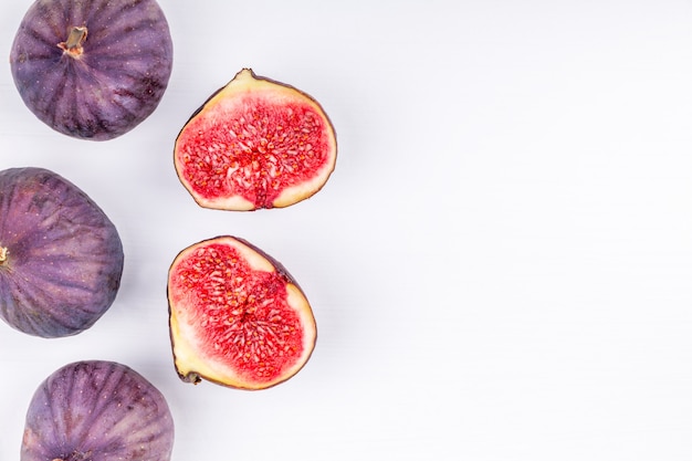 Purple fresh whole and sliced figs on white background