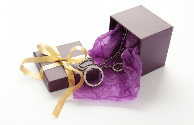 Purple gift box with jewelry and yellow ribbon over white