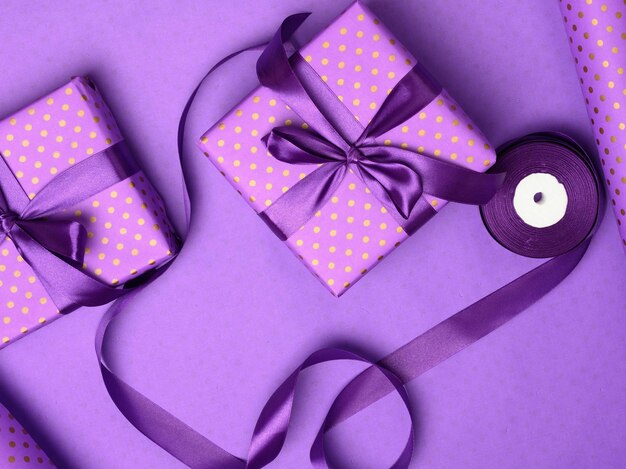 Purple gift box wrapped in silk ribbon on a purple background top view