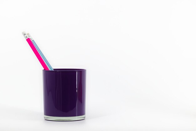 A purple glass desk organizer on a white background holds three pencils with erasers