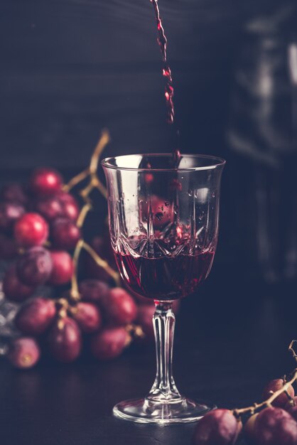 Purple grapes with grape juice in a glass jar, dark picture.