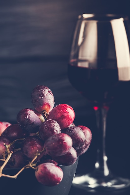 Purple grapes with grape juice in a glass jar, dark picture.