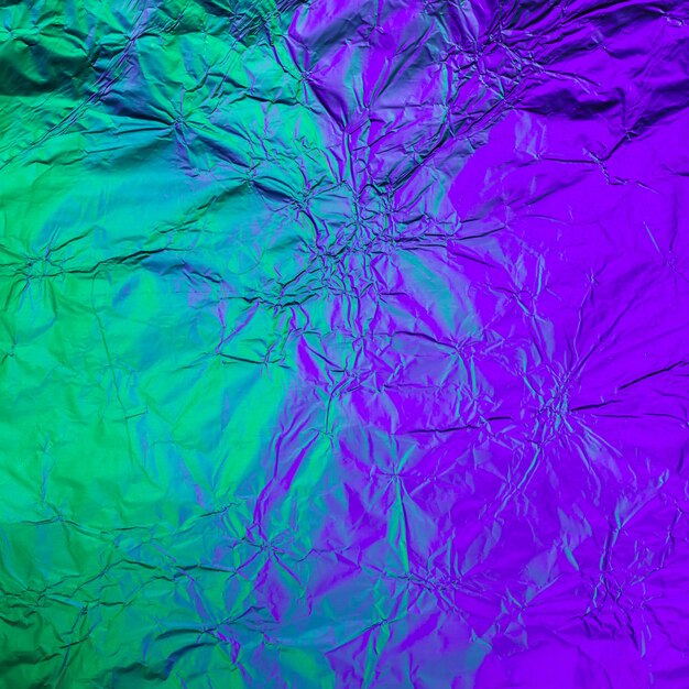 Purple green crumpled background made of illuminated foil. Trendy duotone texture.