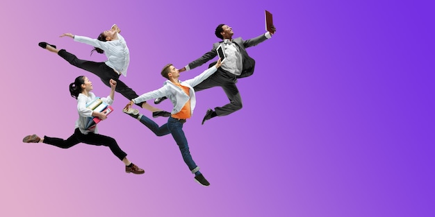 Photo purple. happy office workers jumping and dancing in casual clothes or suit isolated on gradient neon fluid background. business, start-up, working open-space, motion, action concept. creative collage.