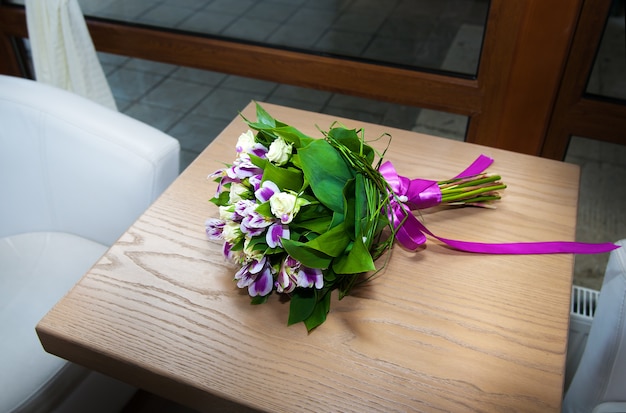 Purple irises bouquet over wooden table