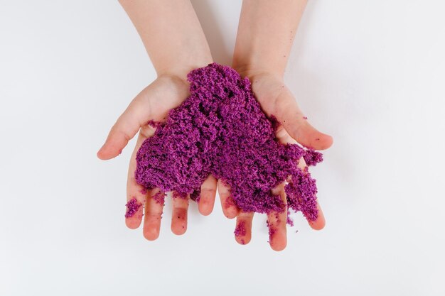 Purple kinetic sand Child sculpts and plays with sand Closeup view White background