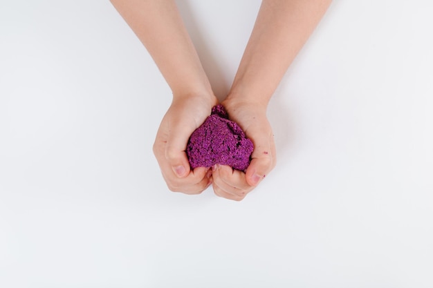 Purple kinetic sand Child sculpts and plays with sand Top view White background Space for text