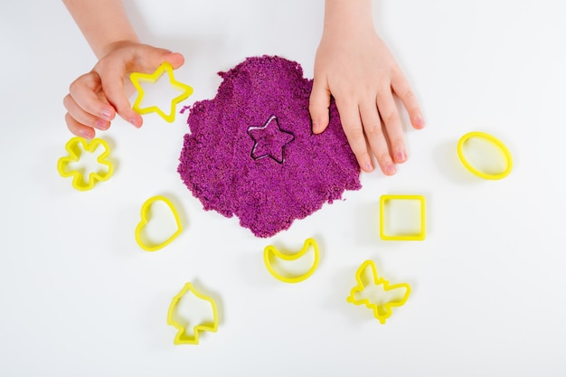 Purple kinetic sand plastic molds for sand. Child sculpts and plays with sand Flat lay