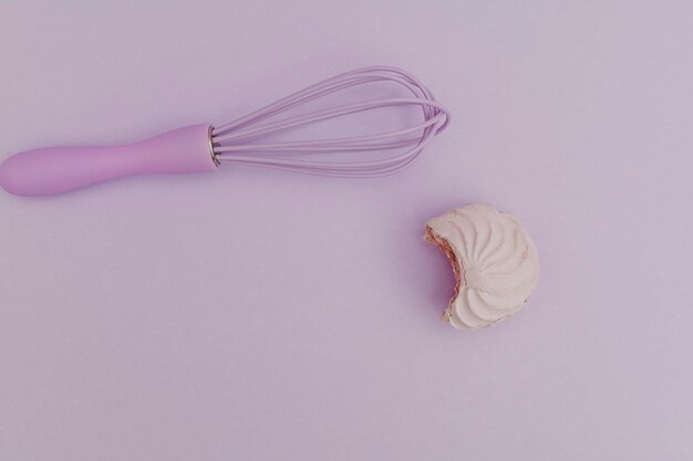 Purple kitchen whisk with marshmallow purple on purple background