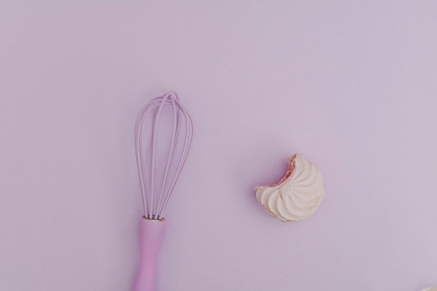 Photo purple kitchen whisk with marshmallow purple on purple background