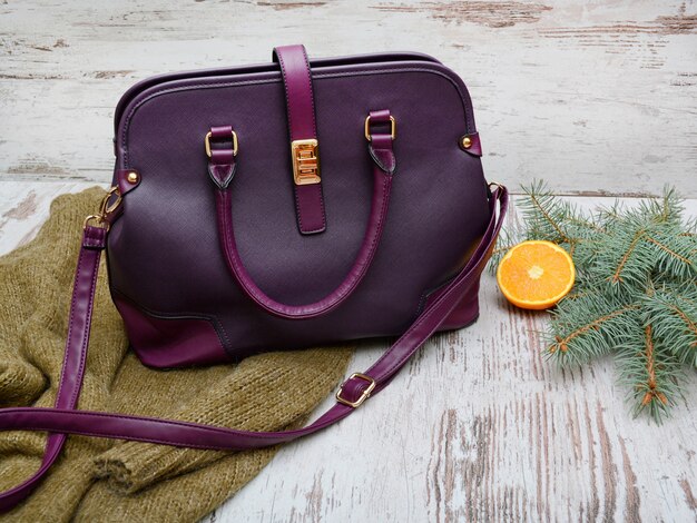 Purple lady bag, warm sweater on a wooden background