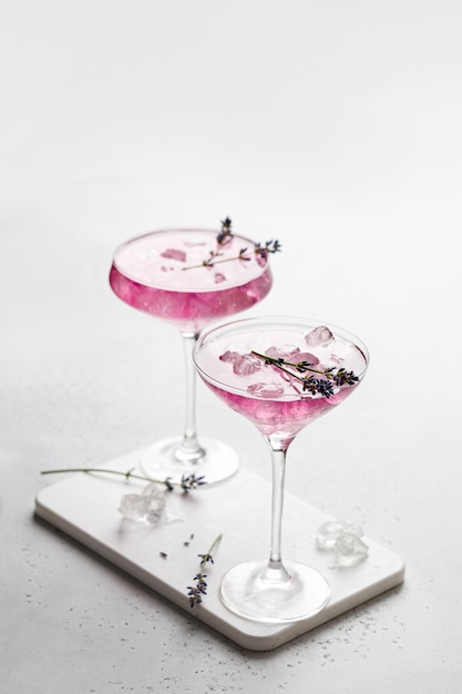 Purple Lavender cocktail drink in a glass on white board and white background with ice and lavender