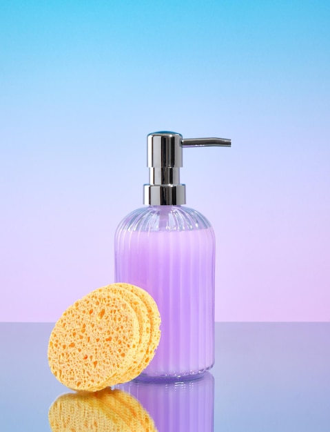 Foto dispenser di sapone liquido viola o schiuma struccante e spugna per la pulizia del viso