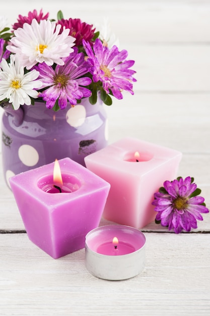 Фиолетовые зажженные свечи и розовые садовые цветы