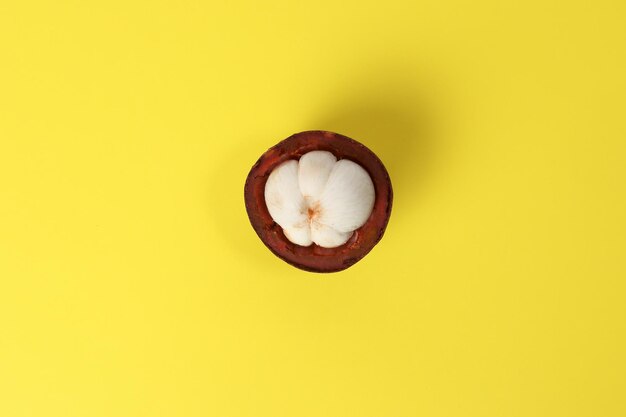 Purple mangosteen fruit pealed half on yellow background