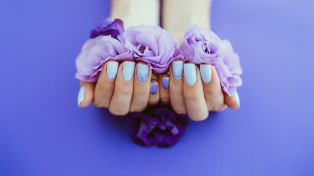 Foto manicure viola su uno sfondo semplice con fiori