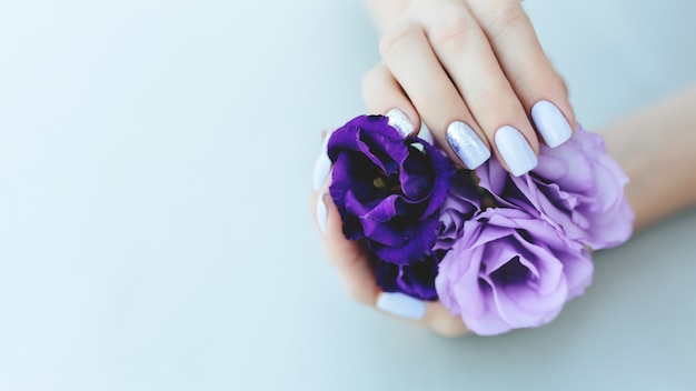 Manicure viola su uno sfondo semplice con fiori