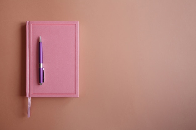 분홍색 노트북 또는 일기, 분홍색 종이에 보라색 금속 펜