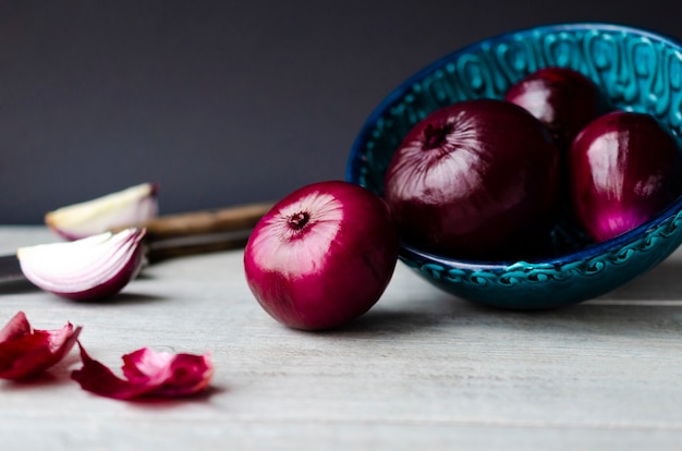 Purple onion vegetable on grey background in grey bowl