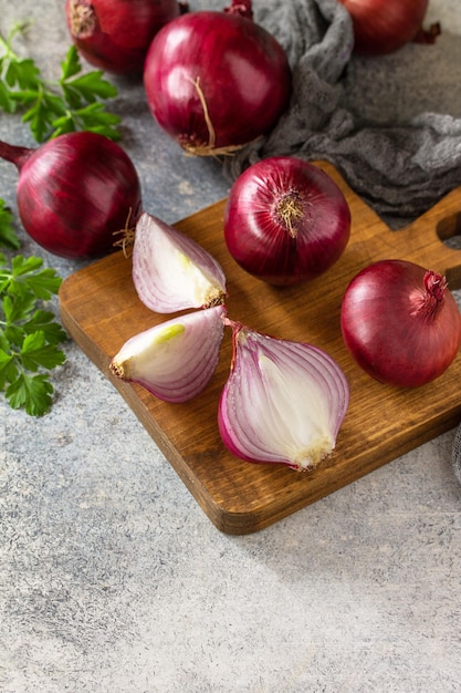 Purple Onions Fresh whole purple onions and one sliced onion on a stone countertop Copy space