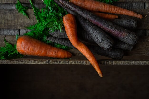 Purple and orange carrots in a wooden crate