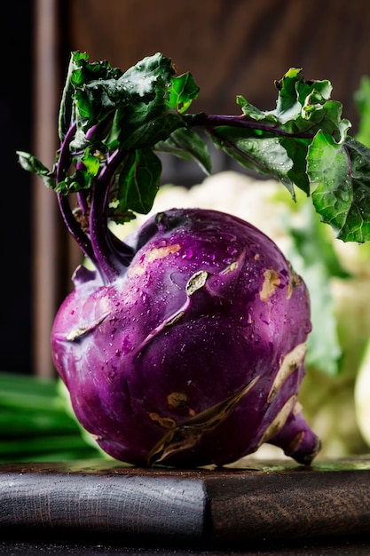 Purple organic fresh kohlrabi cabbage summer harvest on brown kitchen table selective focus