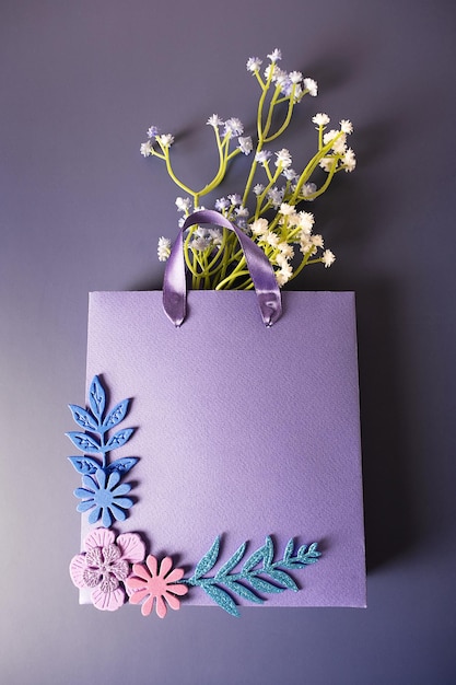 Purple paper bag with handmade flowers on a purple\
background