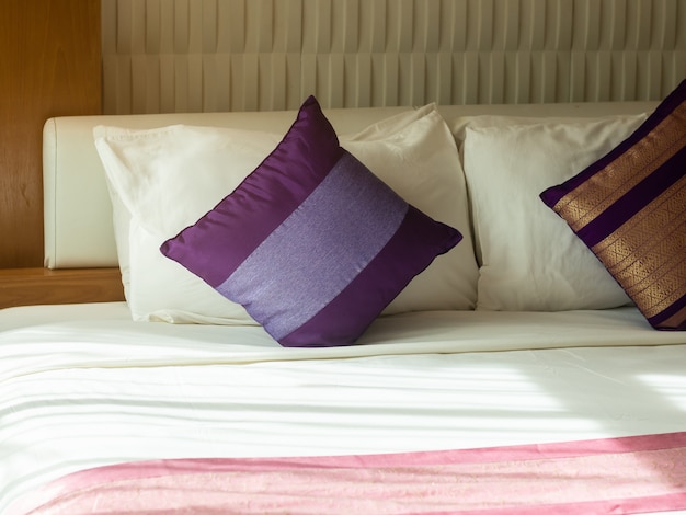 Purple pillow on white bed.