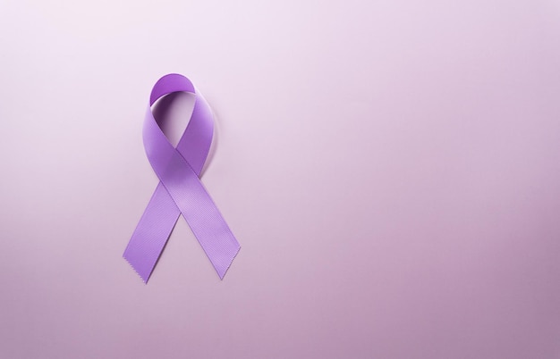 Purple ribbon on pastel paper background for supporting World Cancer Day campaign on February 4