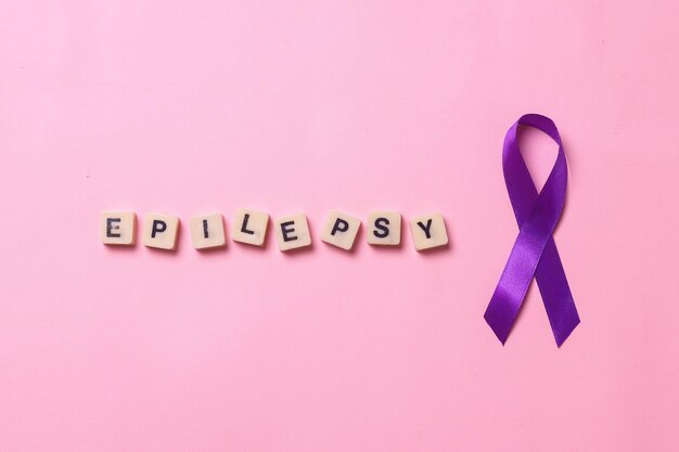 Photo purple ribbon with epilepsy lettering on blocks isolated on pink background