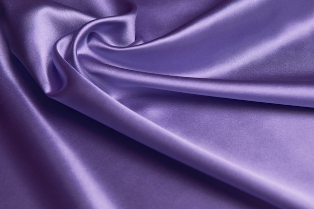 Purple silk fabric background, close-up. Smooth violet satin cloth texture can use as abstract background with copy space