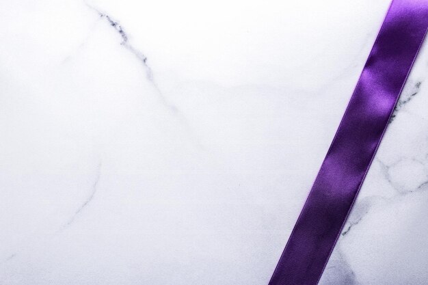 Purple silk ribbon and bow on luxury marble background holiday flatlay backdrop