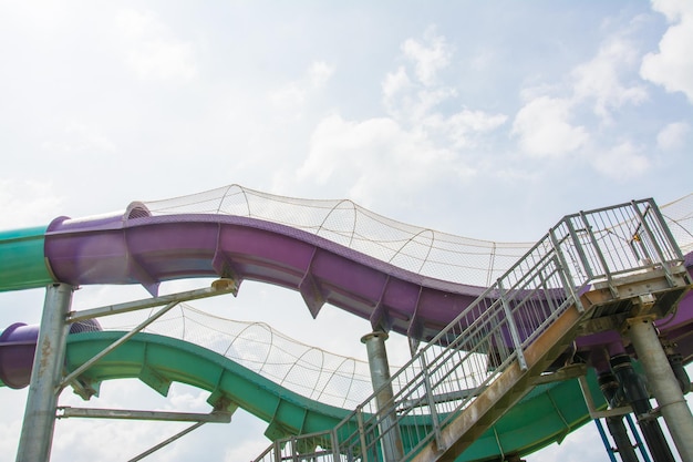 A purple slide is on a roller coaster in a park.