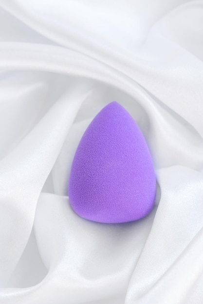 A purple sponge that is laying on a white cloth.