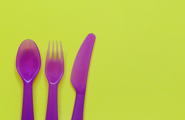 Foto cucchiaio e forchetta viola su colore giallo