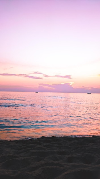 Photo a purple sunset over the sea with a couple walking on the beach.