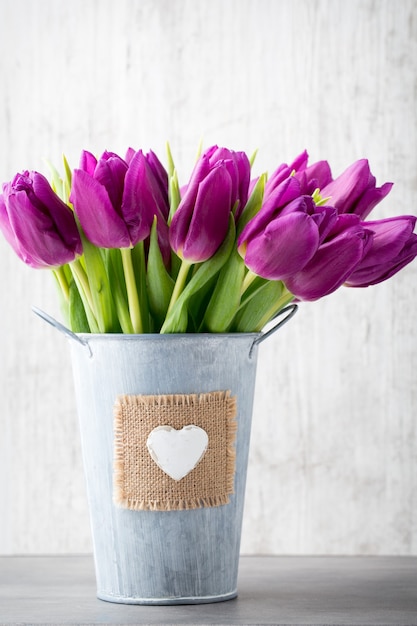 Purple tulip bouquet on the gray wall.