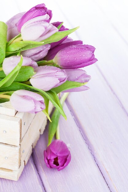 Purple tulips box over wooden table