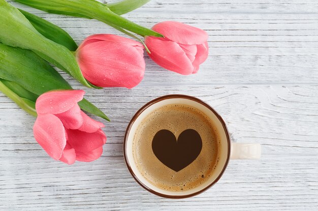 Purple tulips and coffee on wooden table